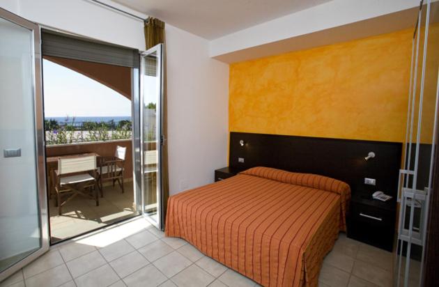 une chambre avec un lit et un balcon avec une table dans l'établissement Hotel Club Ravezzo, à Lido Marini