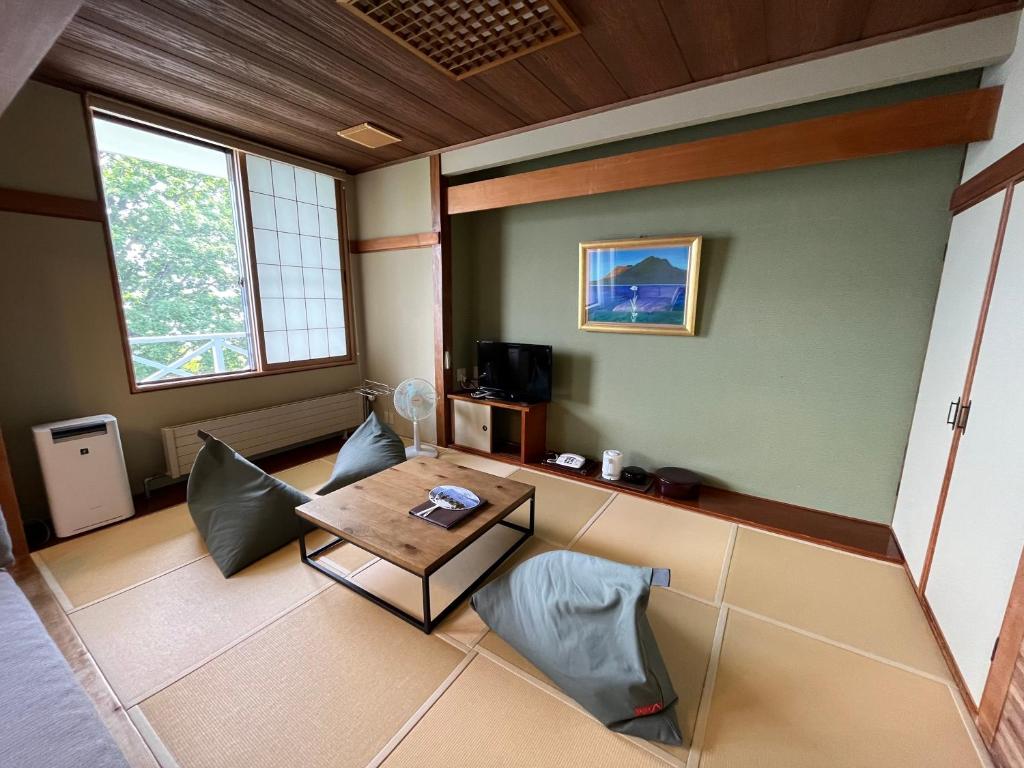un salon avec une table et un canapé dans l'établissement Sapporo's Secret Onsen Sanctuary Marukoma Onsen Ryokan, à Chitose