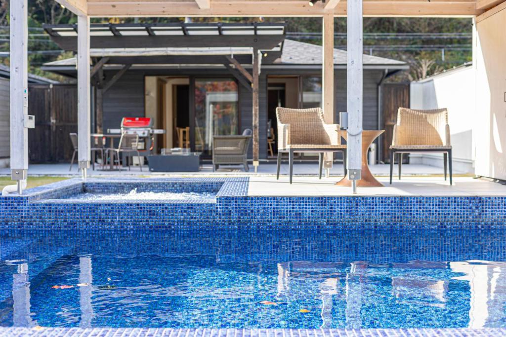 une piscine avec des chaises et une table et une maison dans l'établissement Mezzo ALL SUITE VILLAS, à Miyazu