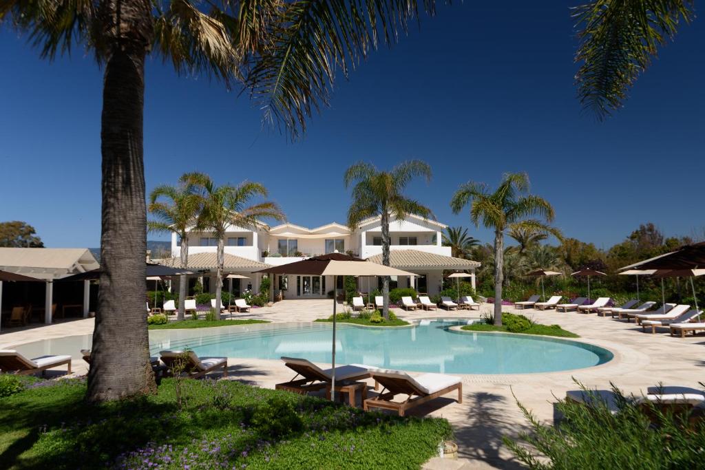 - une piscine avec des chaises longues et des palmiers dans l'établissement Sant Efis Hotel, à Pula