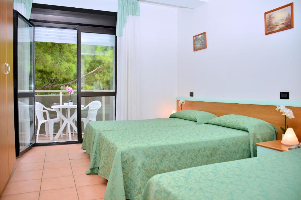 une chambre d'hôtel avec deux lits et un balcon dans l'établissement Hotel Etna, à Lignano Sabbiadoro