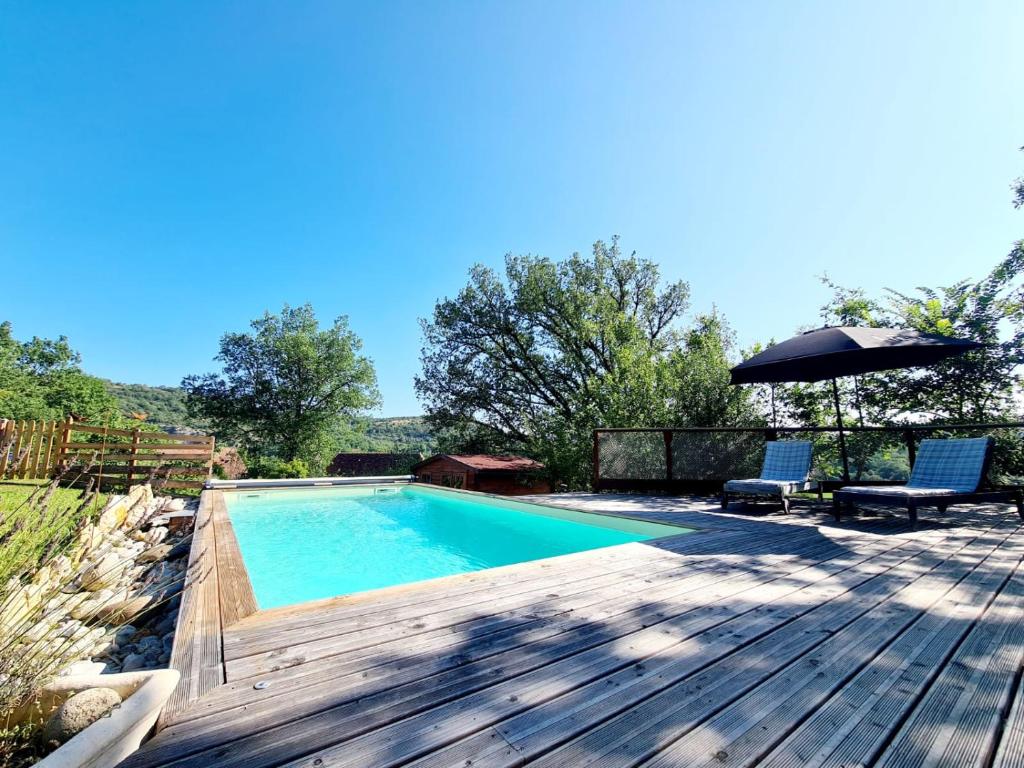 - une piscine avec une terrasse et un parasol dans l'établissement La Roulotte du Coustal, Cajarc, Lot, à Cajarc