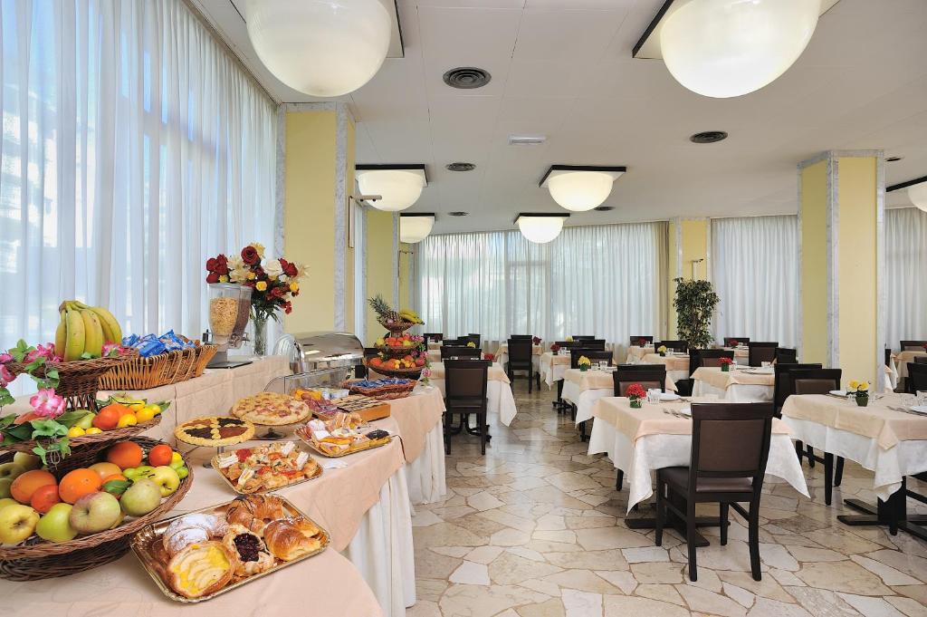 un restaurant avec des tables et des chaises avec de la nourriture dessus dans l'établissement Hotel Tiberius, à Rimini