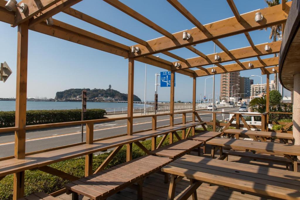 une pergola en bois avec des bancs sur une promenade dans l'établissement Hotel Shiosai, à Fujisawa