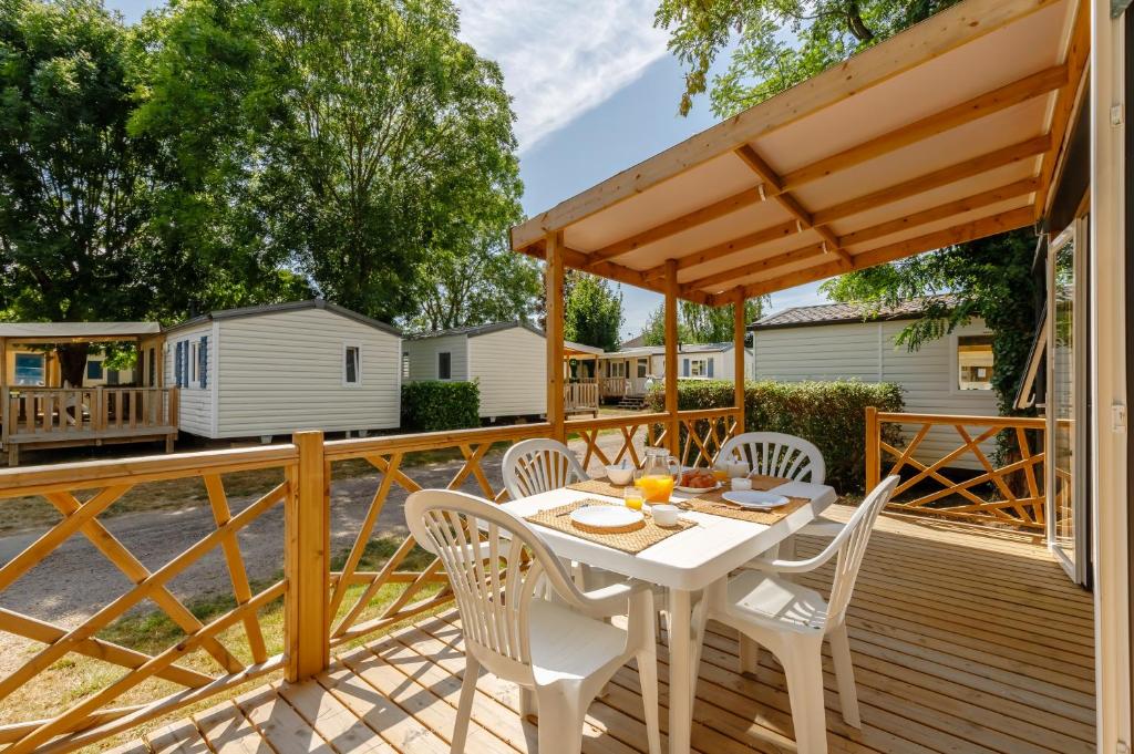 une terrasse en bois avec une table et des chaises blanches dans l'établissement Camping maeva Escapades Sun Océan, à Talmont-Saint-Hilaire