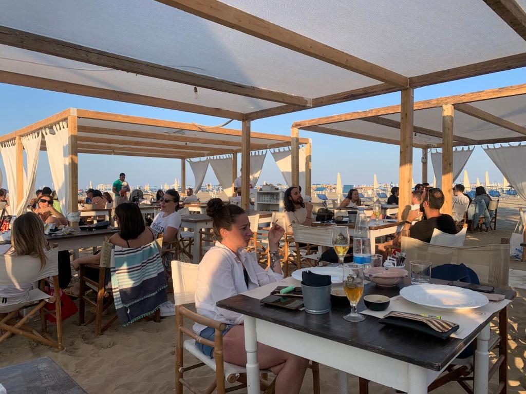un groupe de personnes assises à des tables dans un restaurant dans l'établissement Hotel Migani, à Rimini