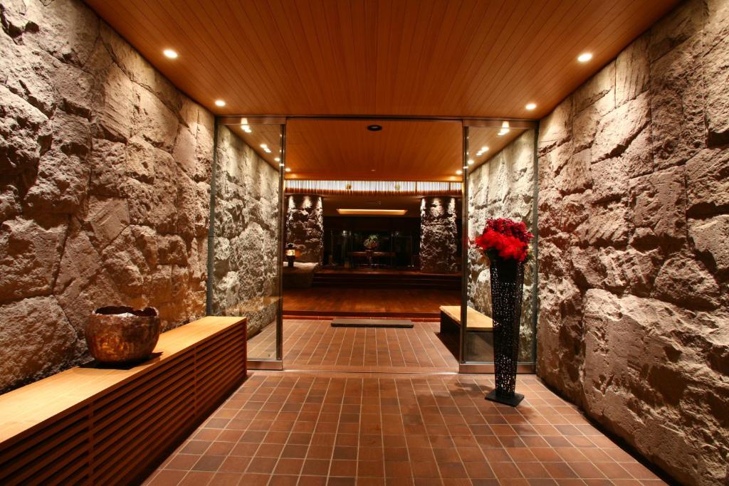 un couloir avec un mur en pierre et un vase de fleurs dans l'établissement Suizantei Club Jozankei-Adults Only, à Jozankei