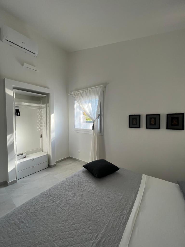une chambre blanche avec un lit et une fenêtre dans l'établissement Villa Giuliana Luxury Home: piscina, solarium, barbecue. A pochi passi dal mare, à Fontane Bianche