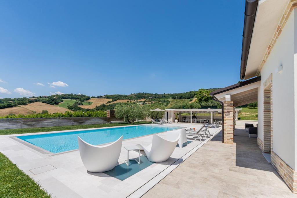 une villa avec une piscine et des chaises blanches dans l'établissement Villa Amore di Ada - Modern Design Villa - AirCo, Private Pool & Near The Beach, à Monterubbiano