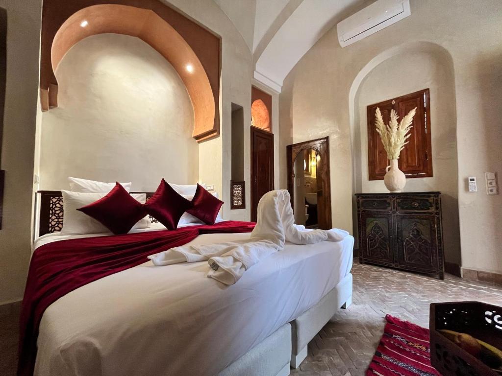 une chambre avec un grand lit avec des oreillers rouges et blancs dans l'établissement Riad Dar Zaouia, à Marrakech