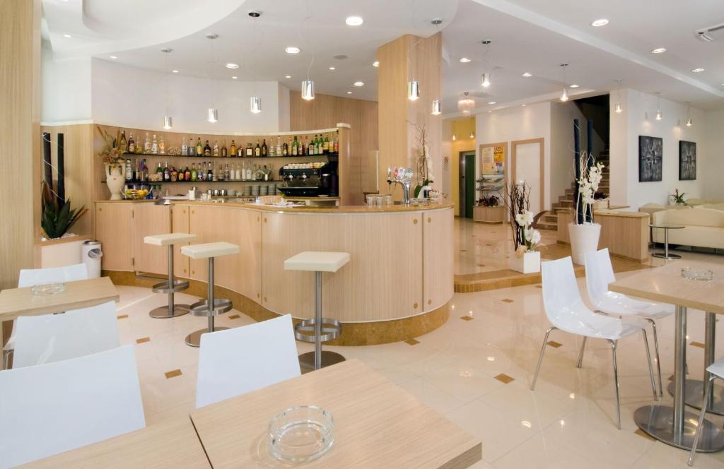 un bar dans un restaurant avec des chaises et des tables blanches dans l'établissement Hotel Olympic, à Misano Adriatico