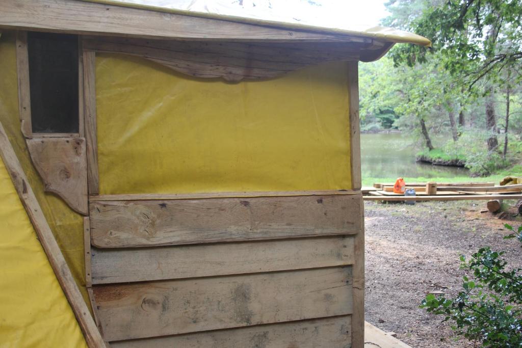 une dépendance en bois avec un toit jaune dans l'établissement air naturel de camping moulin de malesse Tipi, à Saint-Privat