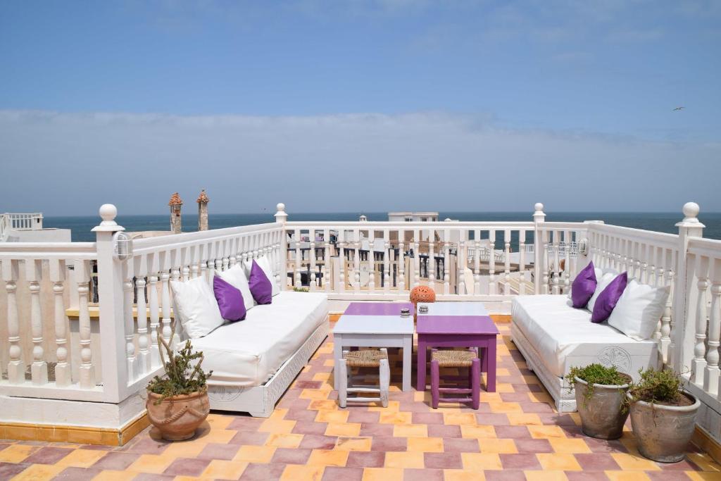 d'un balcon blanc avec des oreillers violets et une table. dans l'établissement Riad Saltana, à Essaouira