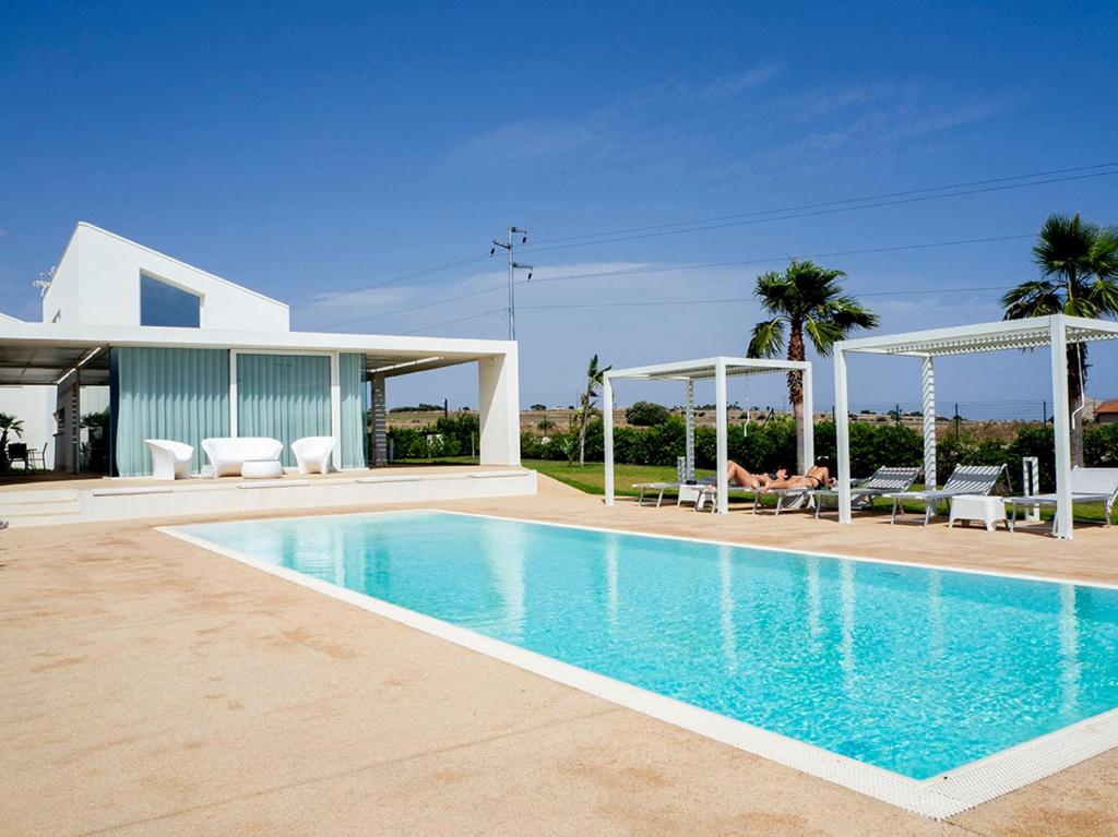 une piscine devant une maison dans l'établissement Villa Arillà con piscina e padel, à Marina di Ragusa