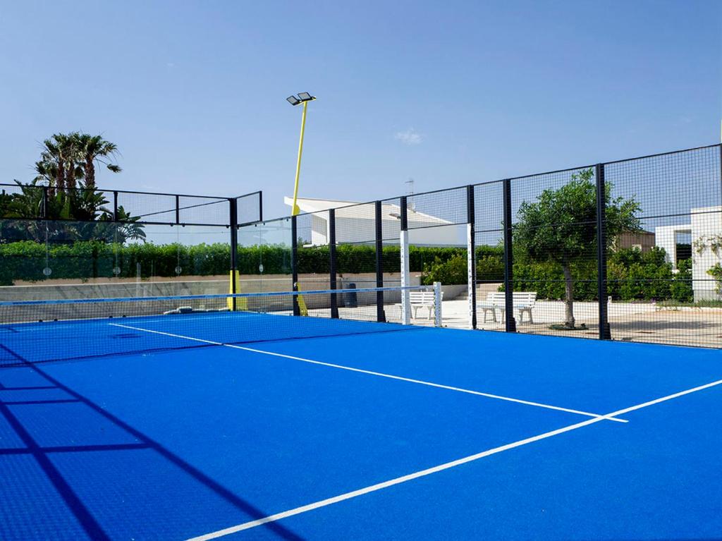 - un court de tennis bleu avec un filet dans l'établissement Villa Arillà con piscina e padel, à Marina di Ragusa