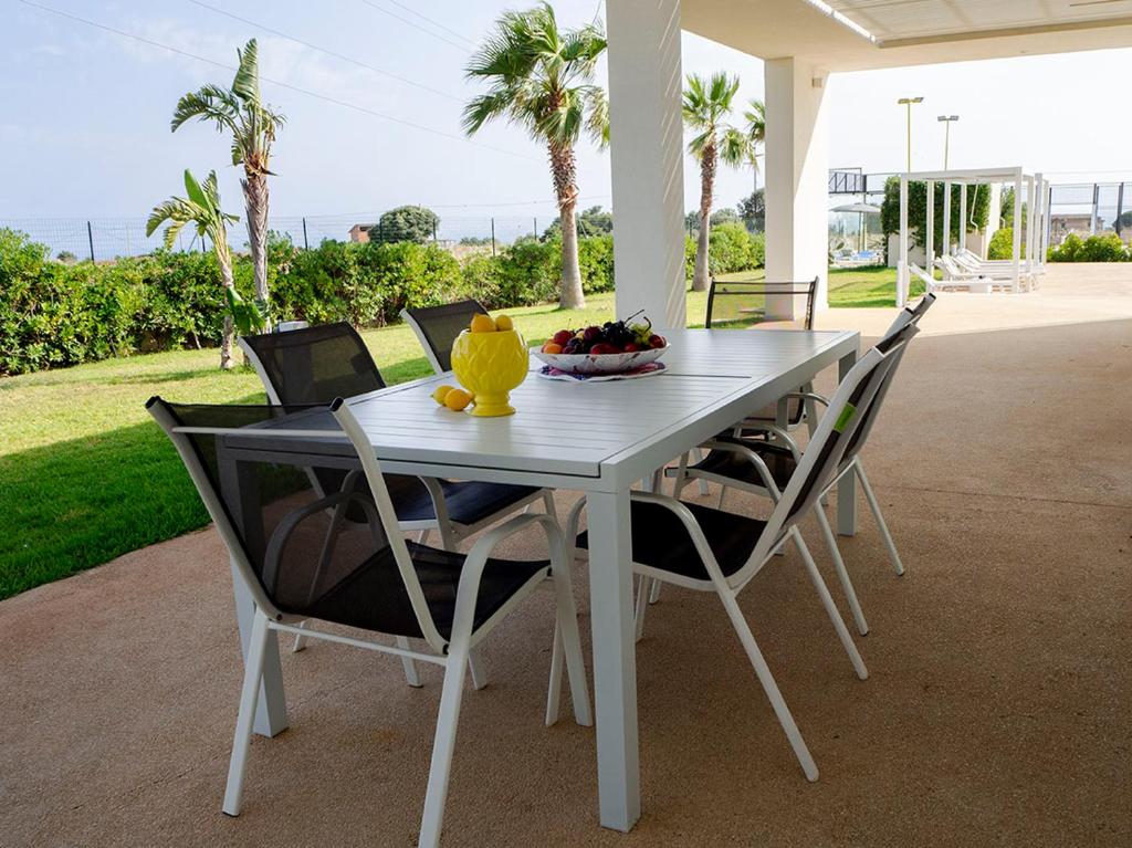 - une table et des chaises blanches avec un bol de fruits dans l'établissement Villa Arillà con piscina e padel, à Marina di Ragusa