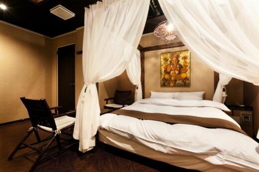 une chambre avec un lit avec des rideaux et une chaise dans l'établissement HOTEL GEN 福知山店, à Kumohara