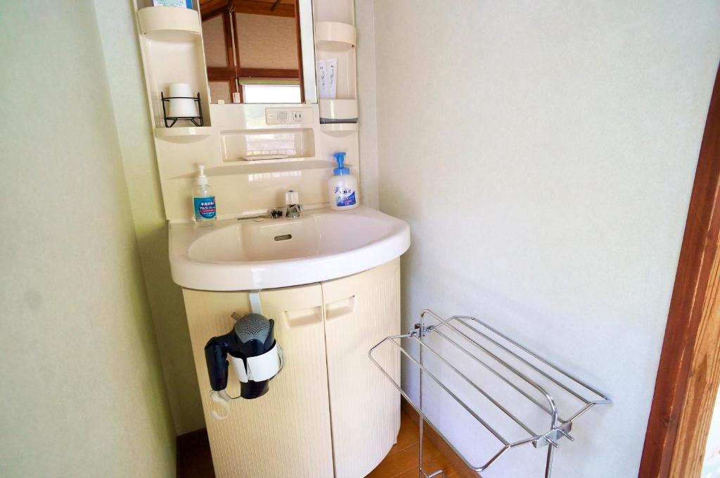 une petite salle de bain avec un lavabo et un miroir dans l'établissement Takaosou, à Yufu 27 autres photos