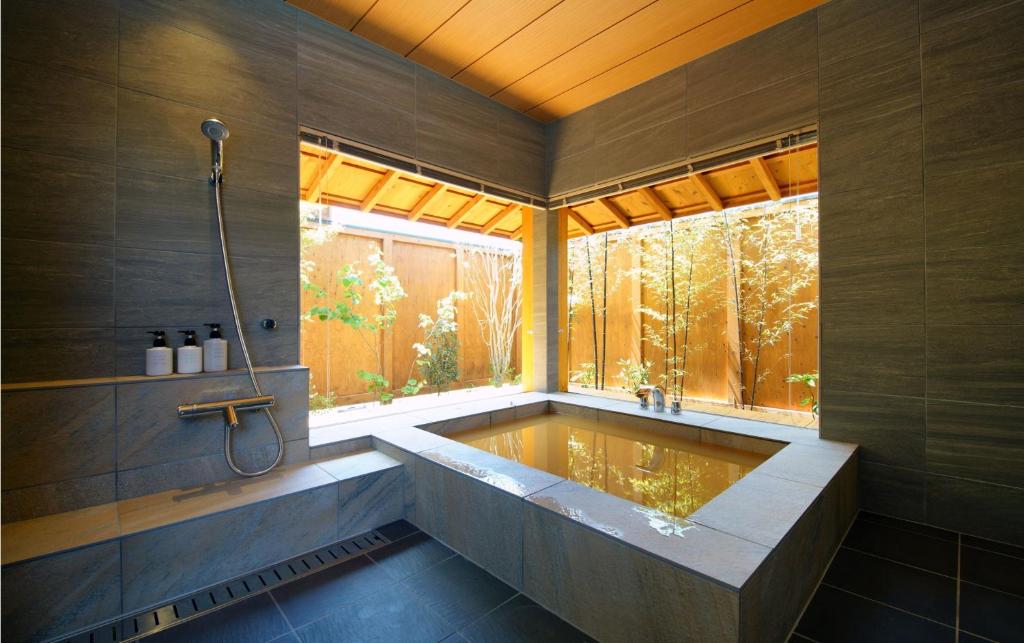 La grande salle de bains est pourvue d'une baignoire et d'une fenêtre. dans l'établissement 瑠璃浜, à Miyazu