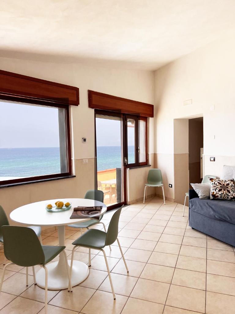 un salon avec une table et des chaises et l'océan dans l'établissement Residenza Fontanelle-Beach Resort, à Santa Maria di Castellabate