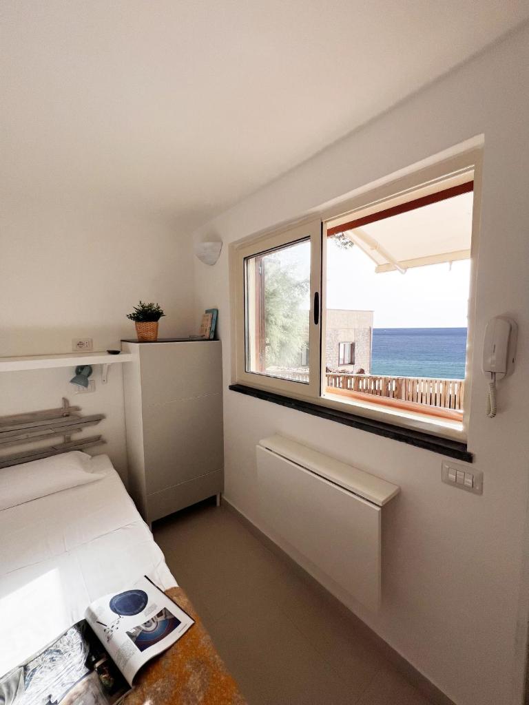 - une chambre avec un lit et une fenêtre offrant une vue sur l'océan dans l'établissement Residenza Fontanelle-Beach Resort, à Santa Maria di Castellabate