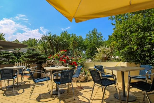 un patio avec tables, chaises et un parasol dans l'établissement Hotel Duca di Kent, à Cesenatico