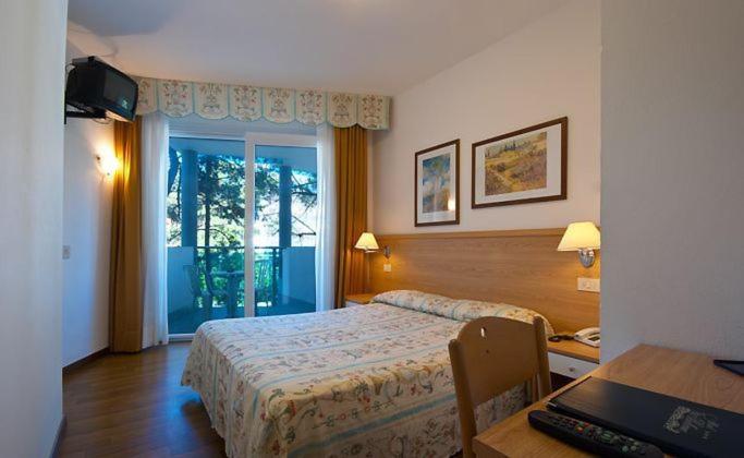 une chambre avec un lit et un bureau avec un ordinateur portable dans l'établissement Hotel Bellevue, à Lignano Sabbiadoro