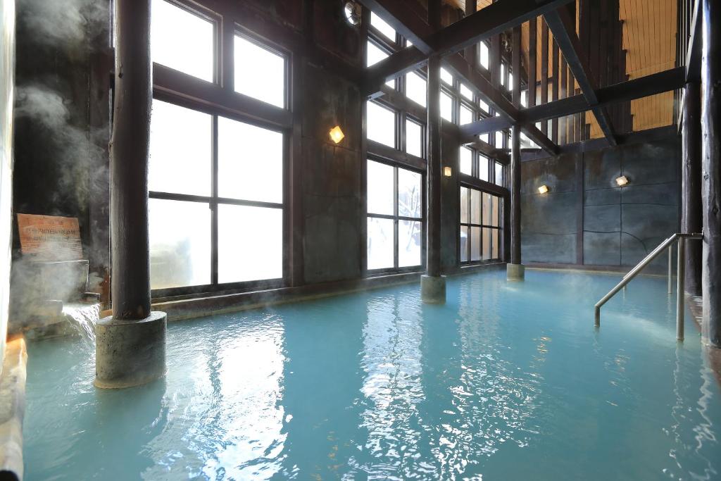 une piscine d'eau bleue dans un bâtiment avec des fenêtres dans l'établissement Hirayunomori, à Takayama