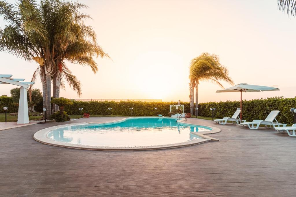 une piscine avec deux chaises et des palmiers dans l'établissement Villa Volare, à Polignano a Mare