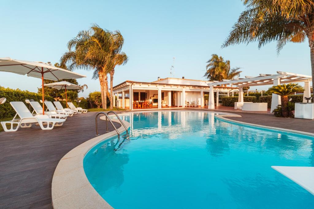 une piscine avec des chaises et une maison dans l'établissement Villa Volare, à Polignano a Mare