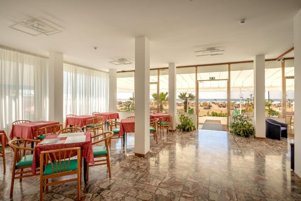 un restaurant avec des tables rouges, des chaises et des fenêtres dans l'établissement Hotel Royal Garnì, à Caorle 42 autres photos