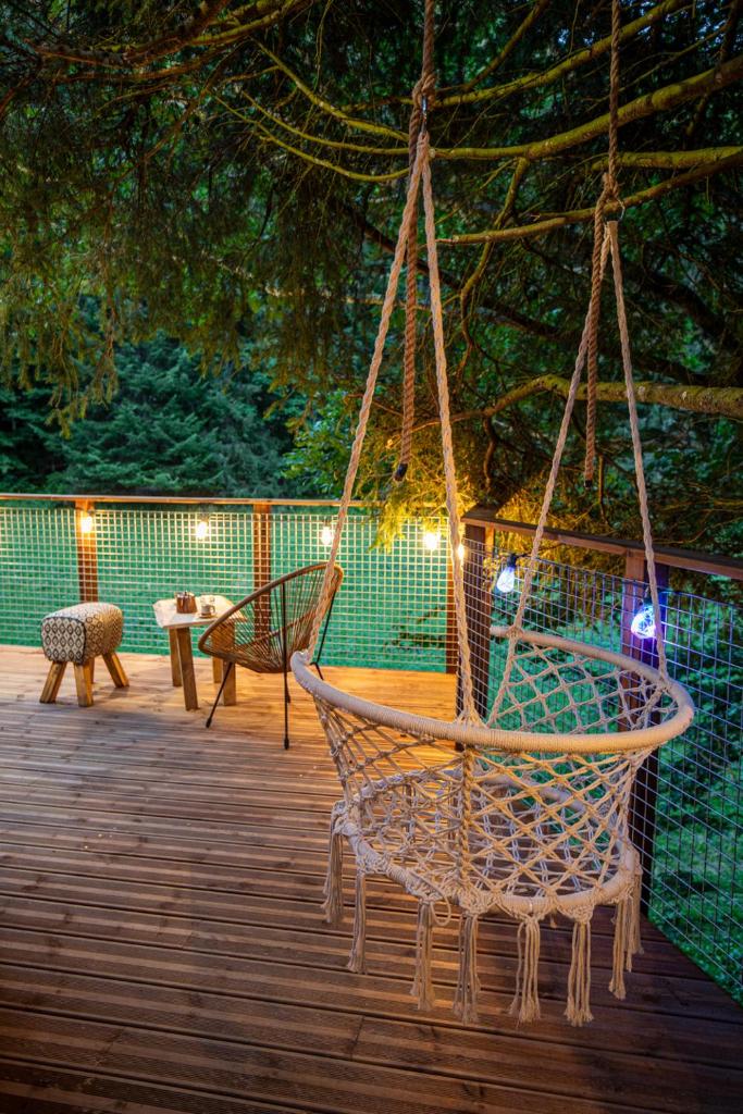 - un hamac sur une terrasse avec une table et des chaises dans l'établissement Dôme panoramique tout confort au cœur du Vercors, à Autrans