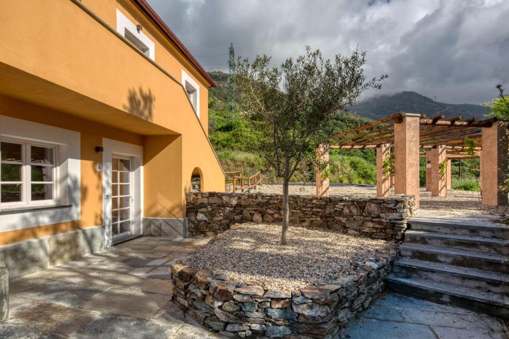 une maison avec un mur de pierre et un arbre dans la cour dans l'établissement Mirandola Suites, à Arenzano
