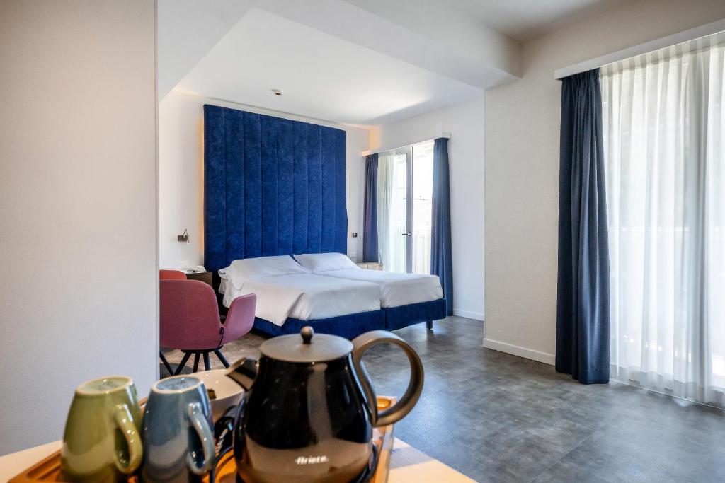 Cette chambre comprend un lit et une table avec une bouilloire. dans l'établissement Hotel Garden Sea Wellness & Spa 4 stelle superior, à Caorle