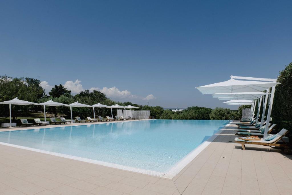 une grande piscine avec chaises et parasols dans l'établissement Casale del Murgese Country Resort, à Savelletri di Fasano
