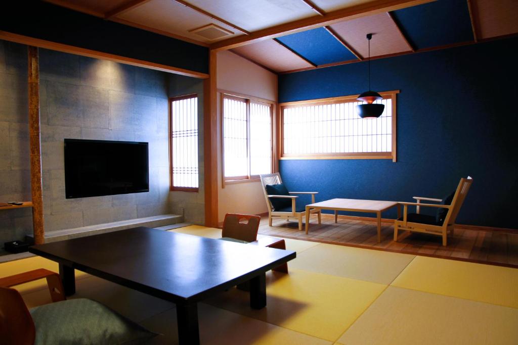 un salon avec une table et une télévision dans l'établissement Ichidaya, à Toyooka