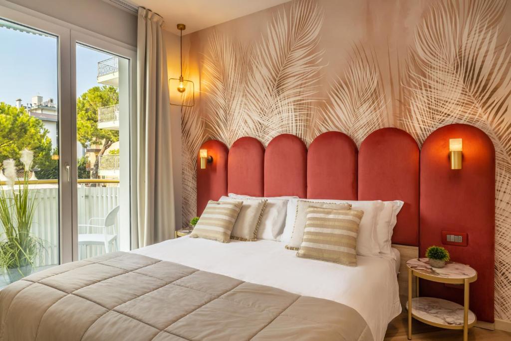 une chambre avec un grand lit avec une tête de lit rouge dans l'établissement Salus Smart & Chic Hotel, à Lido di Jesolo