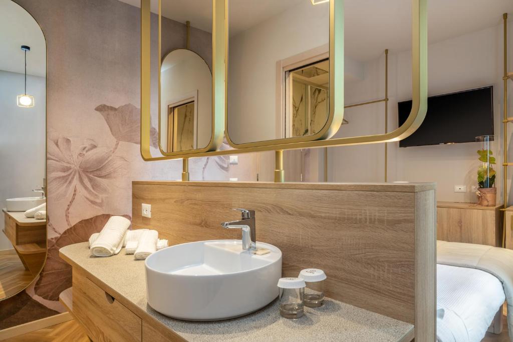 une salle de bain avec un lavabo et deux miroirs dans l'établissement Salus Smart & Chic Hotel, à Lido di Jesolo