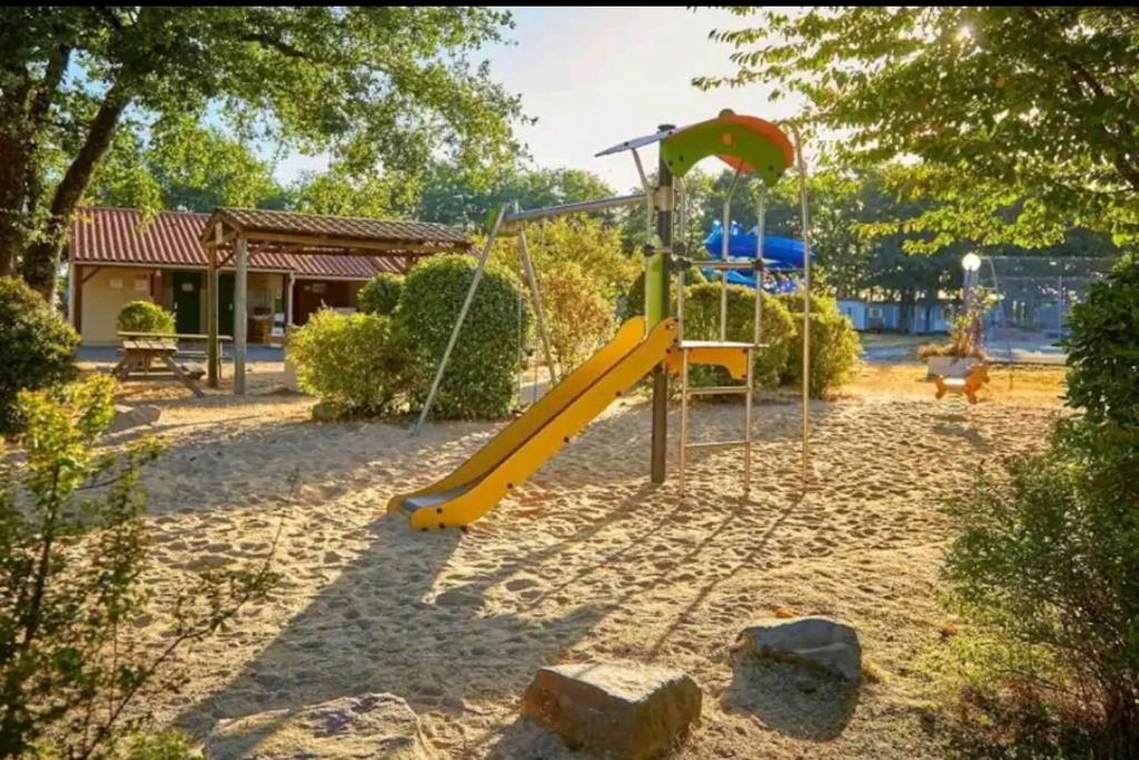 une aire de jeux avec toboggan jaune dans un parc dans l'établissement Mobil Home 6 personnes 3 chambres à 25 MIN Puy duFou, à La Boissière-de-Montaigu