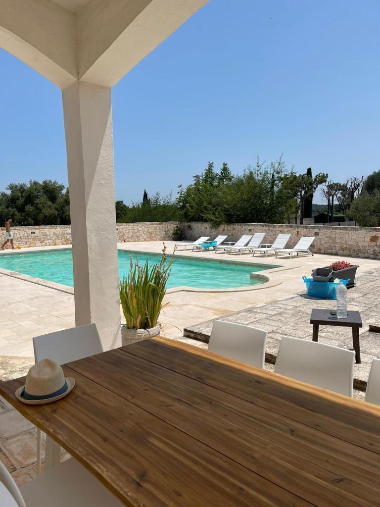 - une table et des chaises en bois à côté de la piscine dans l'établissement Villa Magis, à Ostuni