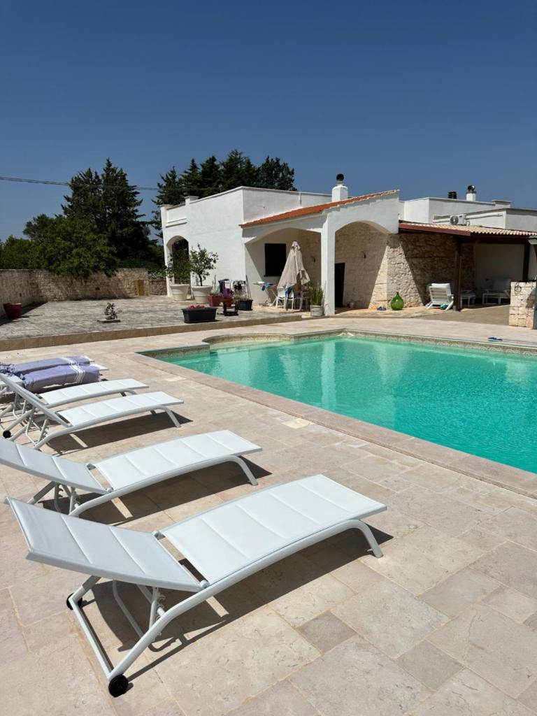 - un groupe de chaises longues à côté de la piscine dans l'établissement Villa Magis, à Ostuni