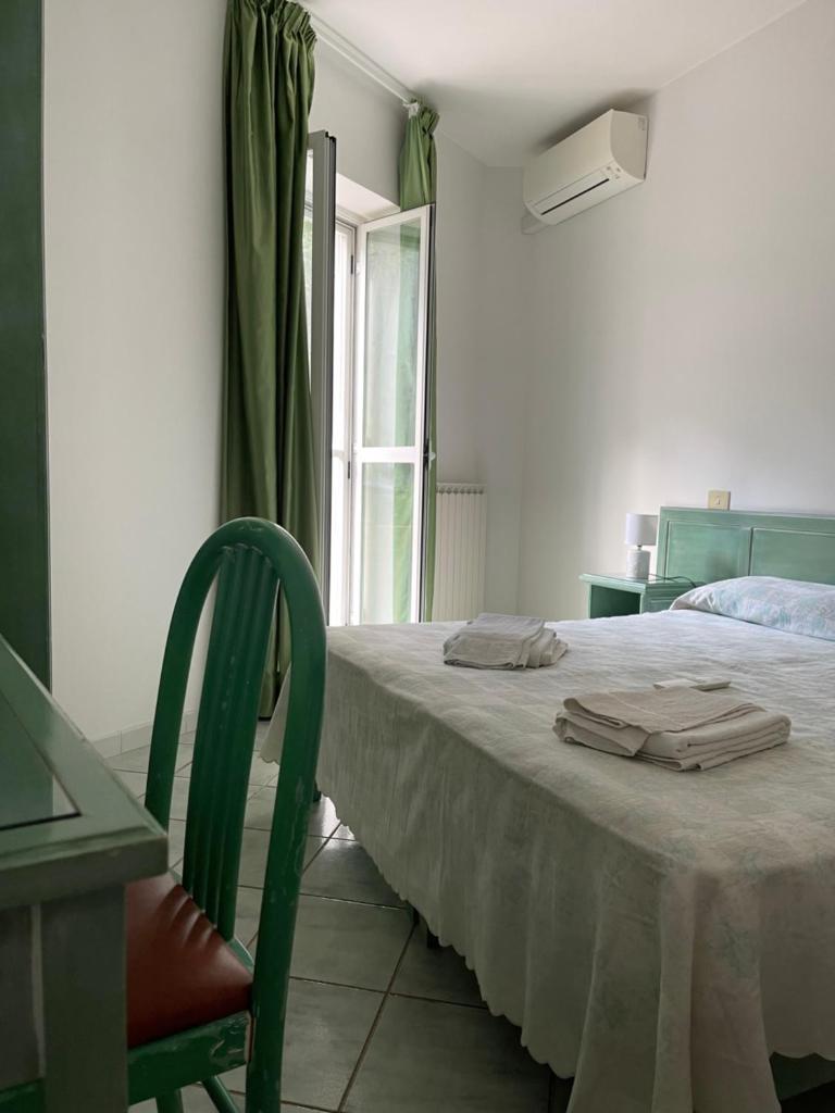 une chambre avec un lit avec une chaise et une fenêtre dans l'établissement Albergo Olmitello - cucina vegetariana bio e tradizionale, à Ischia