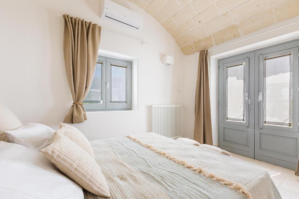 une chambre blanche avec un lit et une fenêtre dans l'établissement Borgo Treffe by Perle di Puglia, à Carovigno