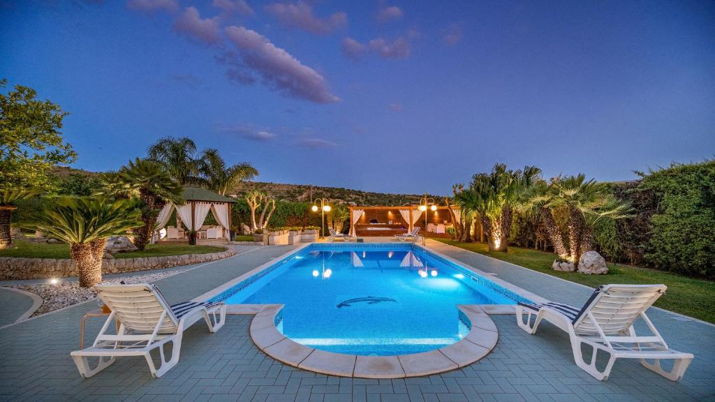 une piscine avec des chaises et une maison dans l'établissement VILLA CUTRERA 8, Emma Villas, à Chiaramonte Gulfi