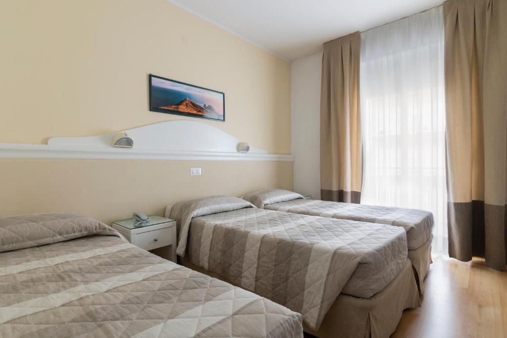 une chambre d'hôtel avec deux lits et une fenêtre dans l'établissement Hotel Miami, à Lido di Jesolo