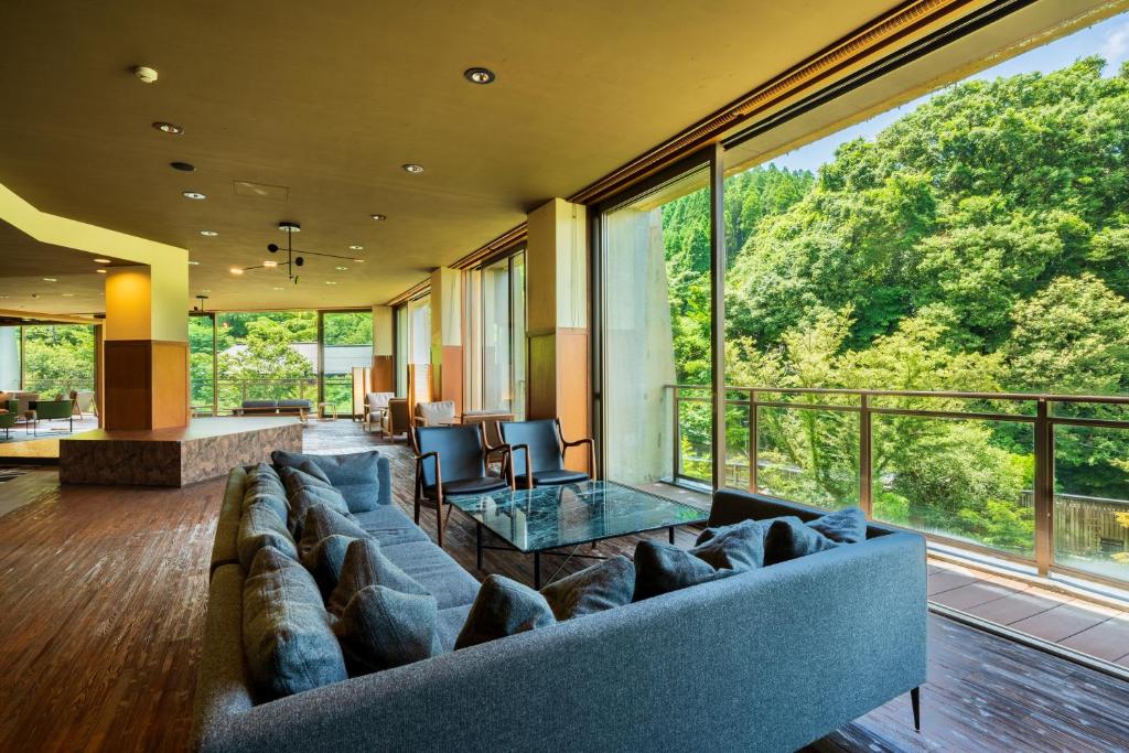 un salon avec un canapé et une table en verre dans l'établissement Yukyo no Hibiki Yusai, à Minamioguni