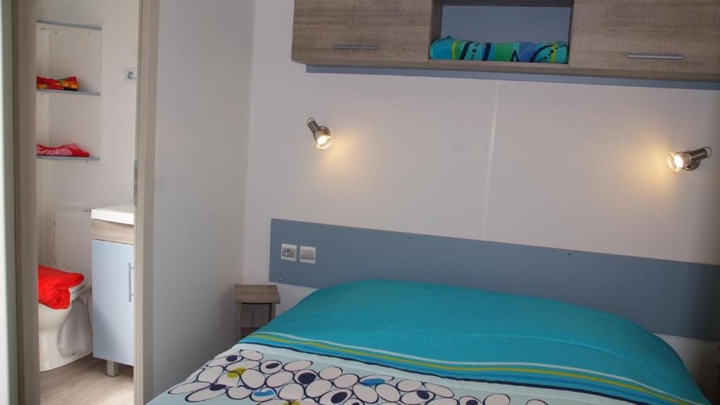 - une petite chambre avec un lit doté d'une tête de lit bleue dans l'établissement MOBILOCAMP, au Muy 3 autres photos