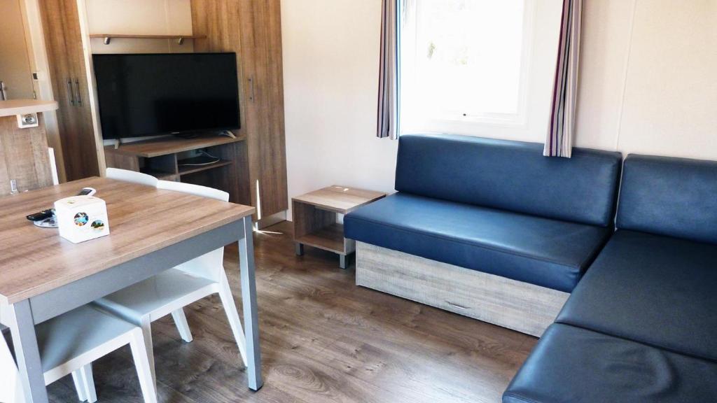 un salon avec un canapé, une table et une télévision dans l'établissement MOBILOCAMP, au Muy
