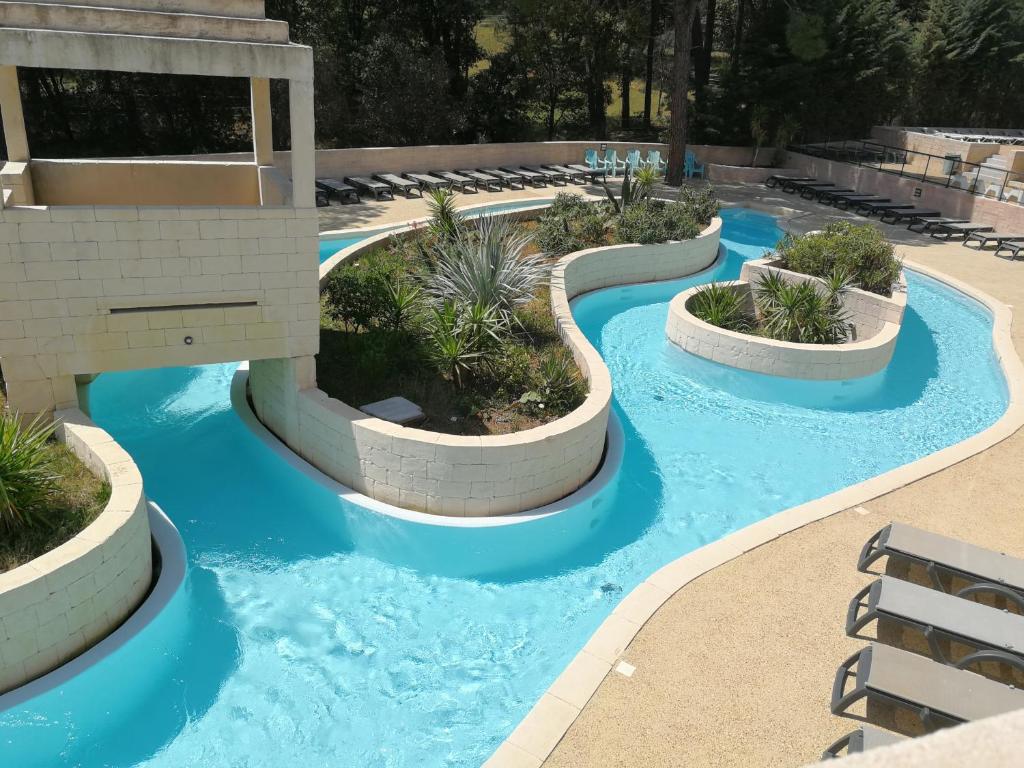 une piscine d'eau bleue et de plantes dans un complexe dans l'établissement MOBILOCAMP, au Muy