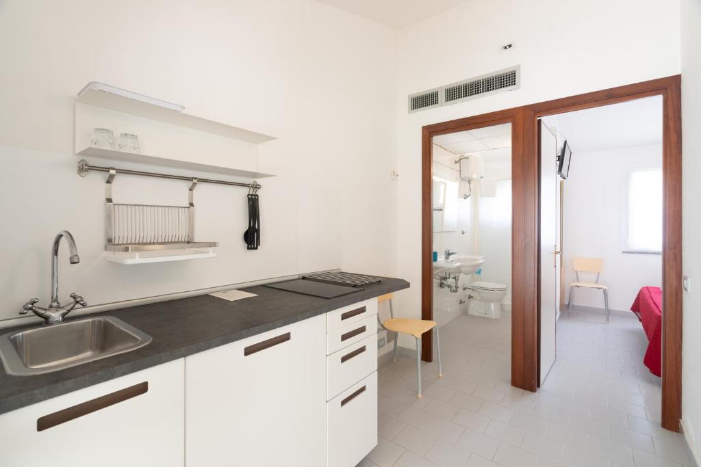 une cuisine avec des placards blancs et un évier ainsi qu'une salle de bains. dans l'établissement Golfo di Maremma Village, à Albinia 105 autres photos